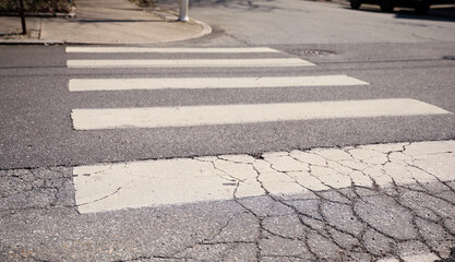 White crosswalk on a busy modern city street, with pedestrian markings and signal lights,...