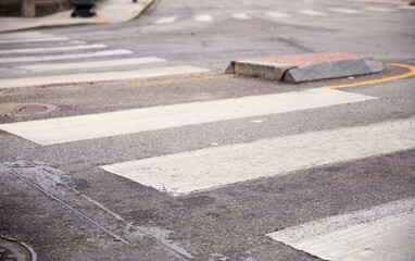 White crosswalk on a busy modern city street, with pedestrian markings and signal lights,...