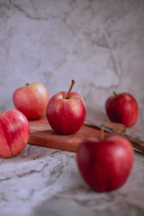 Still life of red apples on wood and white marble.