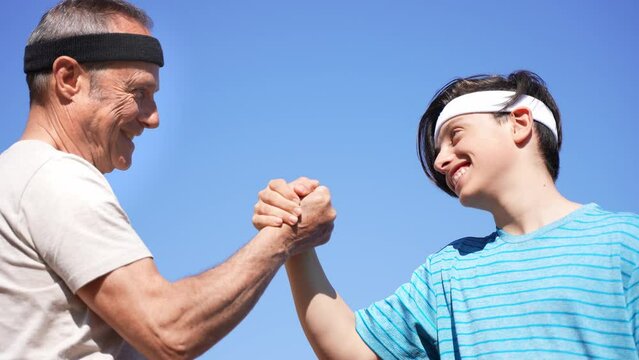 Grandfather and grandson shaking hands before or after a padel match.