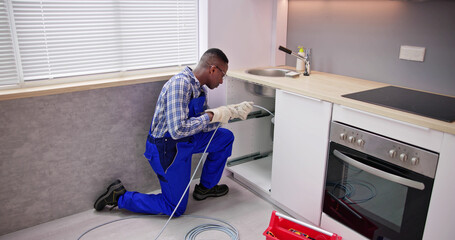 Young Male Plumber Cleaning Clogged Sink Pipe