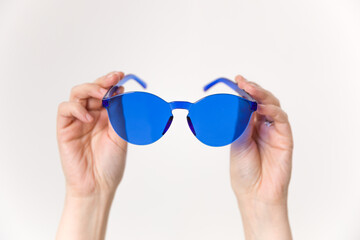 Fototapeta premium The woman's upper hand held up a blue plastic glasses