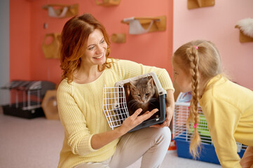 Happy parent and child choosing new pet in animal cat shelter