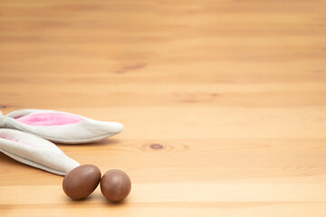 Chocolate eggs, wooden table and Easter bunny ears. Easter background.