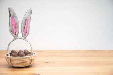 chocolate eggs in a basket with bunny ears. Easter background.