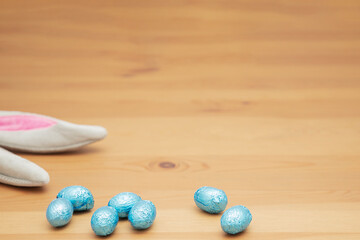 Chocolate eggs, wooden table and Easter bunny ears. Easter background.