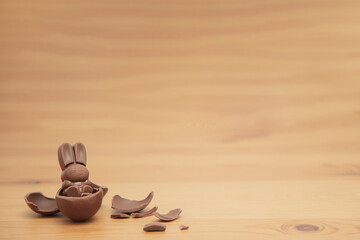 Chocolate baby bunny and chocolate eggs on a wooden table. Easter background.