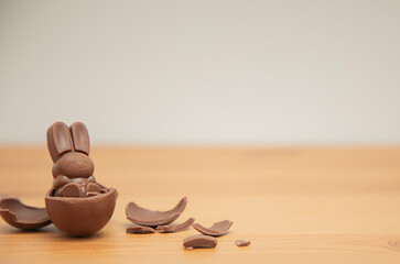 Chocolate baby bunny and chocolate eggs on a wooden table. Easter background.