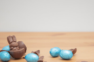 Chocolate baby bunny and chocolate eggs on a wooden table. Easter background.