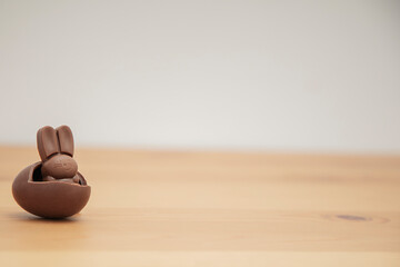 Chocolate baby bunny and chocolate eggs on a wooden table. Easter background.