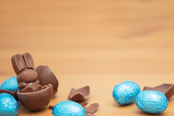 Chocolate baby bunny and chocolate eggs on a wooden table. Easter background.