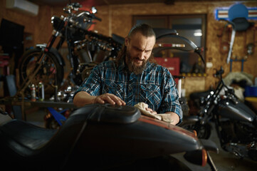 Fototapeta na wymiar Biker cleaning his motorbike in repair shop on weekend