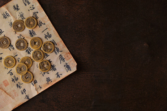 Arrangement of chinese lucky coins for good fortune and success on old chinese manuscript, dark rusty background with copy space