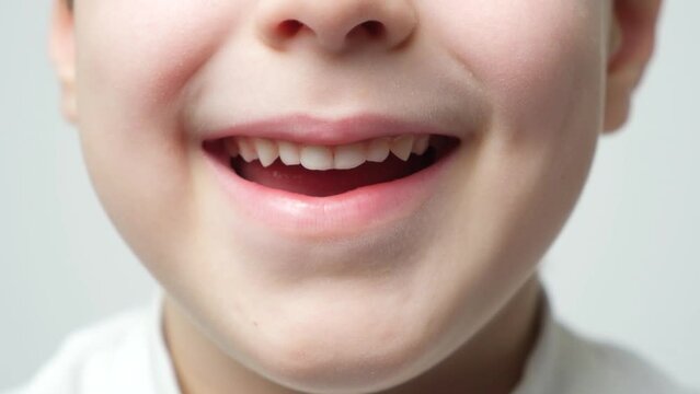 A preschooler's smile, close-up lips. Baby teeth. The child stretches his lips disgruntledly forward
