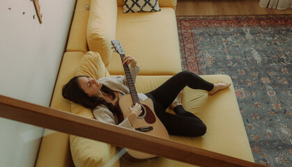 Creative hobby. Talented young female musician sit in armchair alone compose instrumental song using classic guitar. Copy space