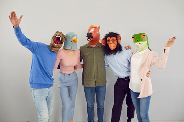 Group of funny and amusing friends pose in various rubber masks in form of animal heads. Portrait...