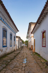 Fototapeta na wymiar Paraty, Brazil. Old street and houses from the colonial period. Stone street floor. Background blue sky.