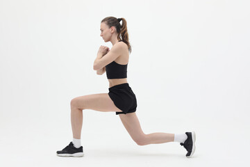 young athletic woman doing lunge exercise isolated on white background, front view