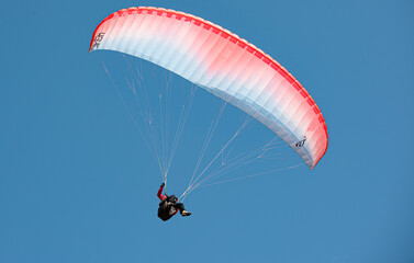 Gleitschirmsegler schwebt vor blauem Himmel, Lauterbrunnental, Kanton Bern, Schweiz