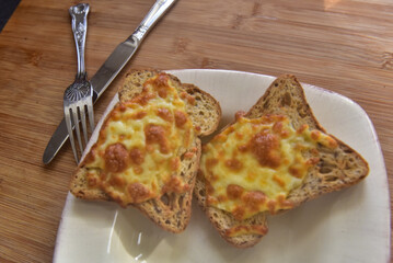 Crispy, Bubbly Cheese on Toast. White plate, knife and fork