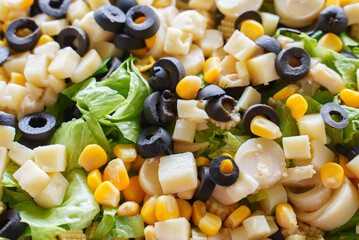 Closeup of an assorted salad made with corn, olives, palm heart and lettuce.