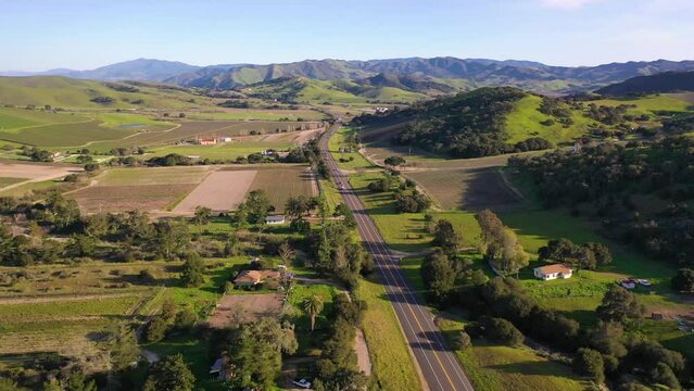 2023 - Excellent aerial footage of cars driving through greenery towards the mountains on a sunny day in Lompoc, California.