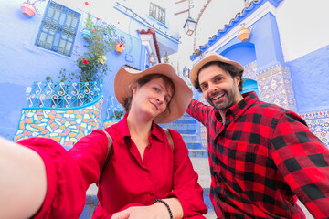 Happy young couple tourist taking selfie on a street in Medina of the blue town of Chefchaouen,...