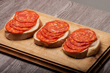 Salami on slices of bread served on a wooden board