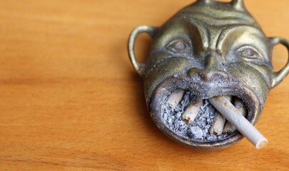 an old antique devil shaped ashtray with a cigarette in it