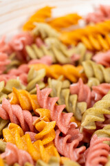 Rice vegetable pasta in the form of spirals in a bowl. Healthy rice pasta with tomatoes, selenera, carrots and beets