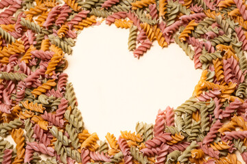 Rice vegetable pasta on a white background, laid out in the shape of a heart, a place for text.