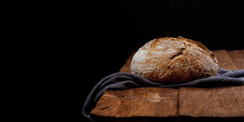 Wheat artisan sourdough bread on a wooden table black background. Panoramic view, free space for text 