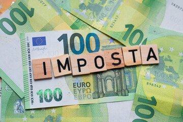 inscription Imposta which means tax in Italian next to euro banknotes. Concept showing the Italian...