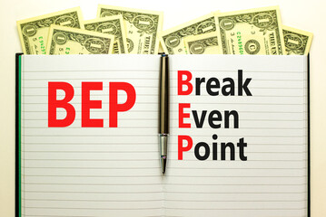 BEP break even point symbol. Concept words BEP break even point on white note on a beautiful background from dollar bills. Pen. Business and BEP break even point concept. Copy space.