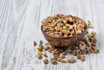 Nuts peeled pistachios in a wooden cup on a white wooden background. Rustic style. The concept of vegetarian and diet snacks.
