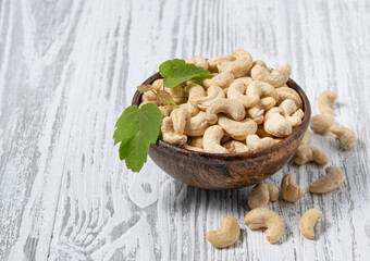 Nuts cashew in a wooden cup on a white wooden background. Rustic style. The concept of vegetarian and diet snacks.