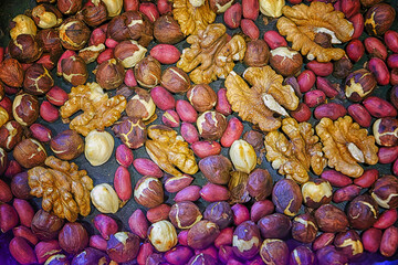 A mixture of roasted walnuts, hazelnuts and peanuts in a pan close-up.