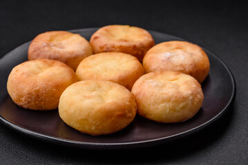 Delicious fresh cottage cheesecakes with raisins and vanilla on a black ceramic plate