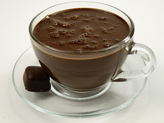 Dark hot chocolate  in a transparent glass cup,  and chocolate candies