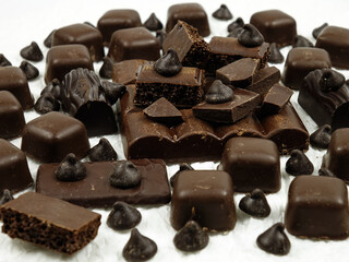 Assortment of milk and dark chocolate products on a wnite table, background