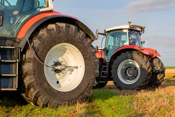 Rear view of modern agricultural tractor on the field. Industrial details. Side view of  red tractor. Close up of wheels - obrazy, fototapety, plakaty