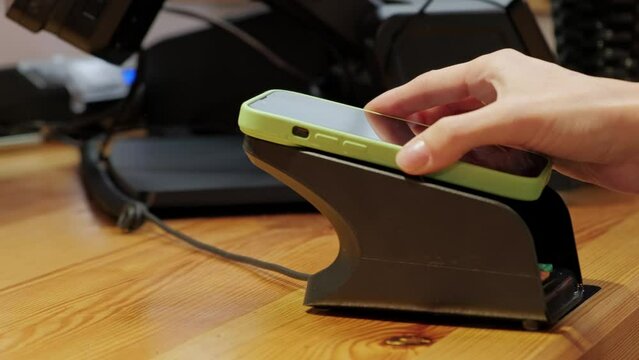 Close up video of customer paying with phone via payppass in cafe.