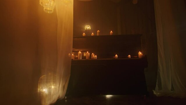 In a background of darkness, a witch performs a mystic rite with black candles and voodoo magic. A close-up of the piano keys amplifies the paganism and magic of the ritual