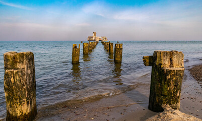 Old ruined wooden pier and a sandy beach	