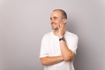 Cheerful handsome man is holding hand on his chin while looking aside.