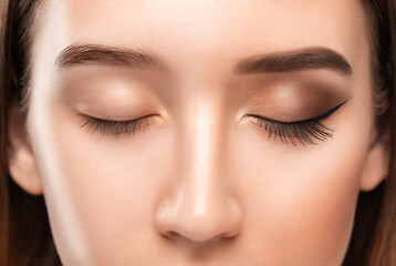 A young beautiful girl removes makeup with a cotton pad and micellar water from her face and eyes.