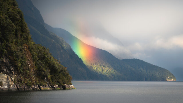 A vibrant rainbow glows in the morning light out in the Doubtful Sound of New Zealand.