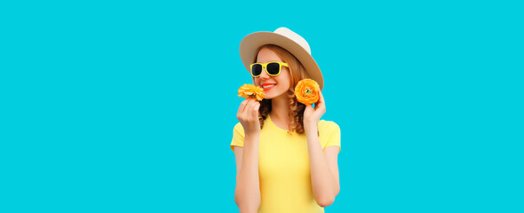 Summer portrait of happy smiling young woman with flower buds wearing round straw hat on blue background