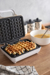 The process of making homemade Belgian waffles. A waffle iron with ready-made Belgian waffles and a...