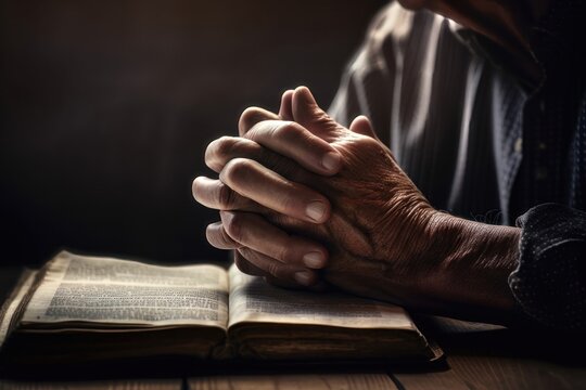 Hands folded in a prayer over a holy book. AI generated